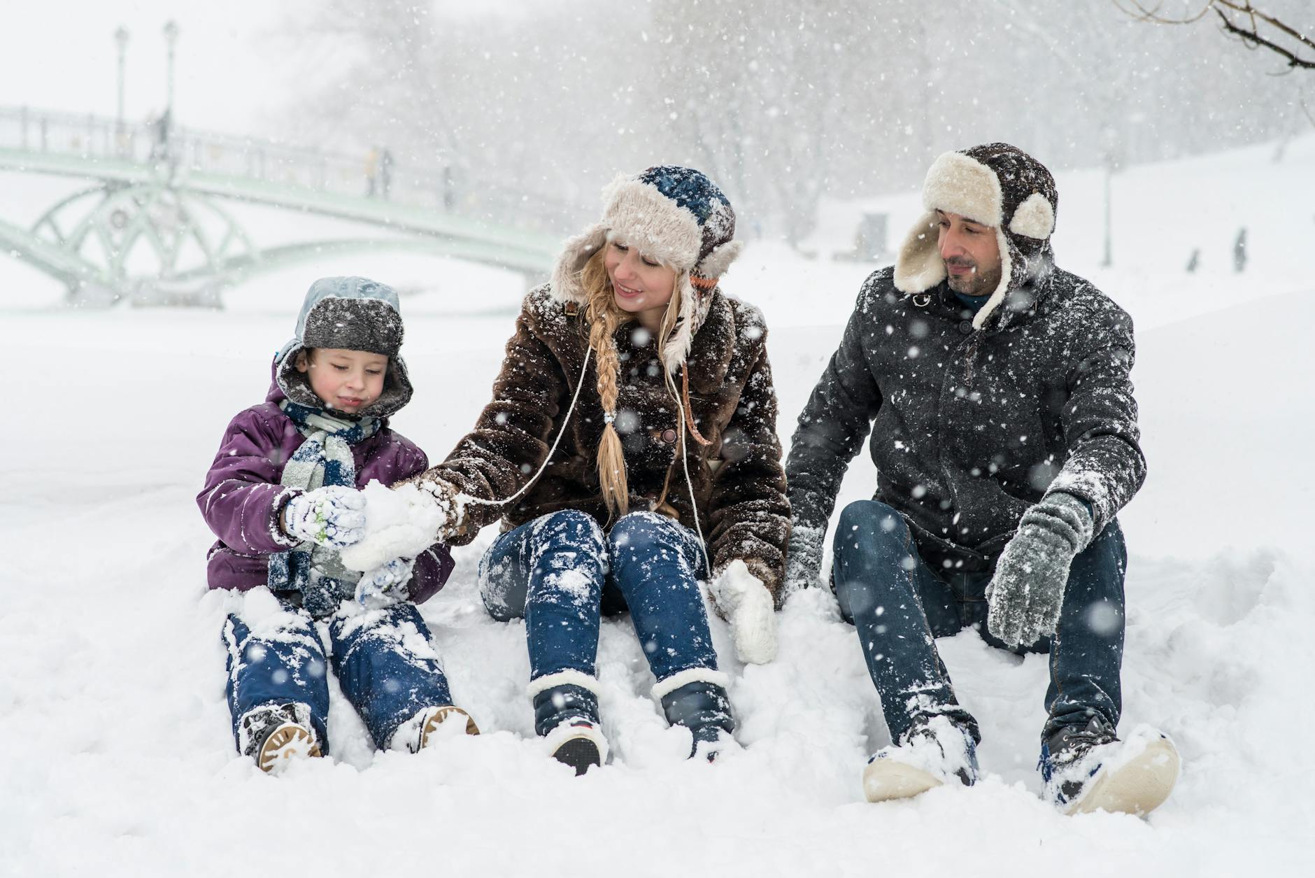 woman man and girl sitting on snow